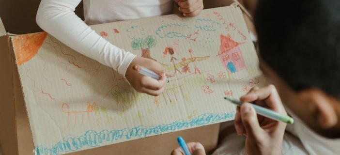 Parent and child drawing on a cardboard box