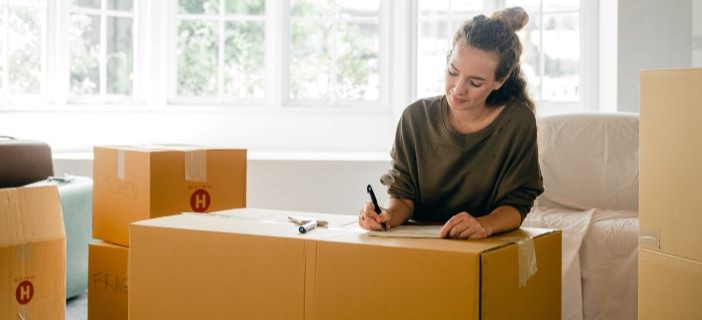 woman writing on cardboard box